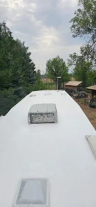 A white trailer featuring a roof and multiple windows, set against a neutral background.