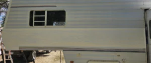 A white RV parked in a grassy field under a clear blue sky.