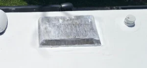 A white van featuring a white roof and a white roof rack, parked in a clear outdoor setting.